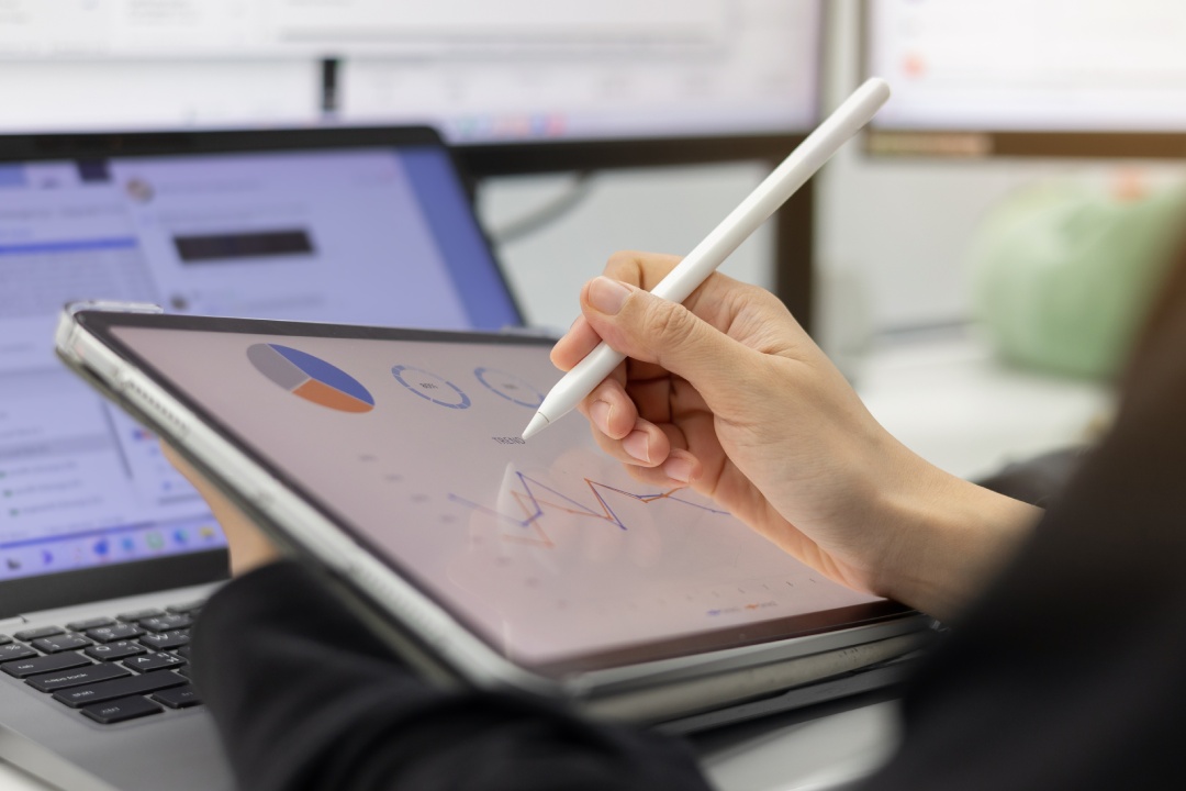 close up manager woman hand using stylus pen to pointing on tablet screen to show company profit and roi summary monthly in the private room for business strategy concept